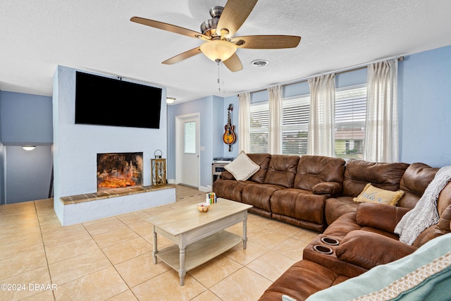 tiled living room featuring ceiling fan, a textured ceiling, and a wealth of natural light