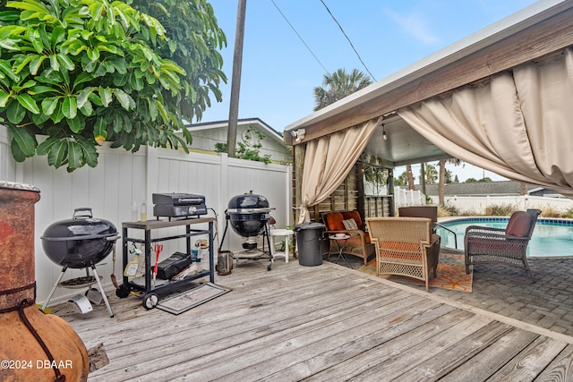 deck featuring a fenced in pool and area for grilling