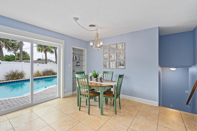 dining room with built in shelves, light tile patterned floors, a textured ceiling, and a notable chandelier