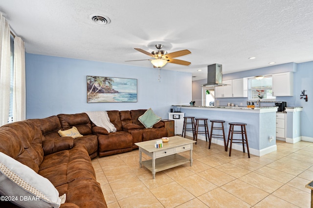 tiled living room featuring a textured ceiling and ceiling fan