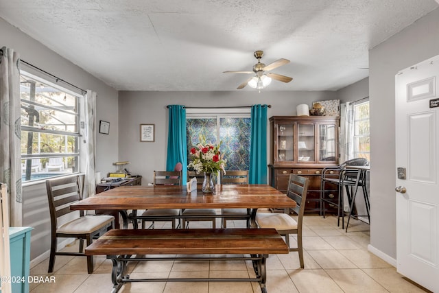 dining space featuring light tile patterned floors, ceiling fan, baseboards, and a textured ceiling