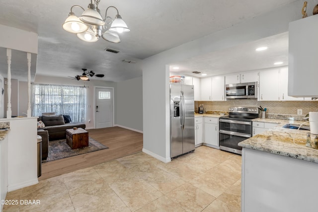 kitchen featuring stainless steel appliances, visible vents, decorative backsplash, open floor plan, and white cabinetry