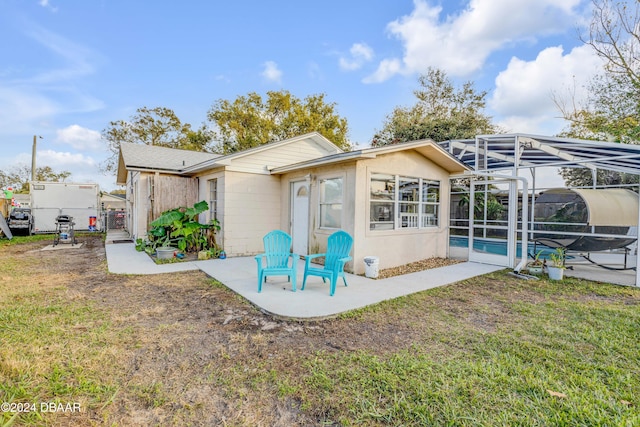 back of house with glass enclosure, a lawn, a patio area, and an outdoor pool