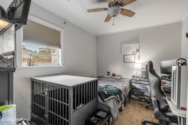 carpeted bedroom with concrete block wall, crown molding, and ceiling fan