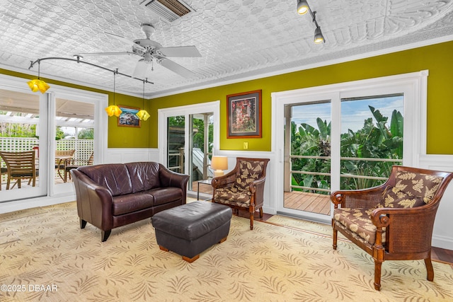 4026 Cardinal Blvd, Wilbur-By-The-Sea, FL 32127 - carpeted living room with rail lighting, plenty of natural light, a ceiling fan, ornamental molding, and wainscoting