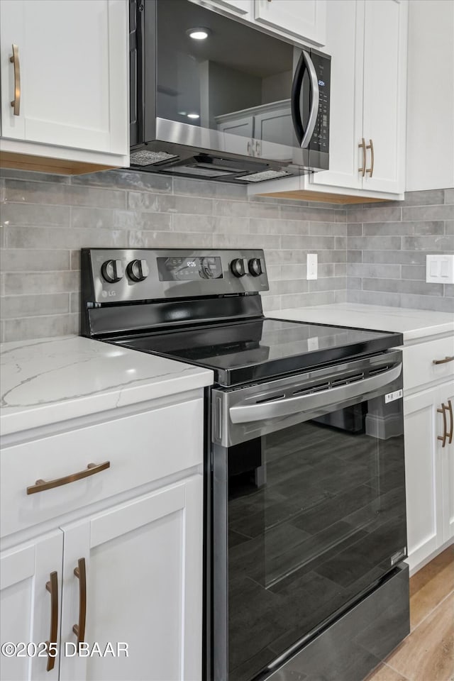 kitchen featuring light hardwood / wood-style flooring, white cabinetry, electric range, light stone counters, and decorative backsplash