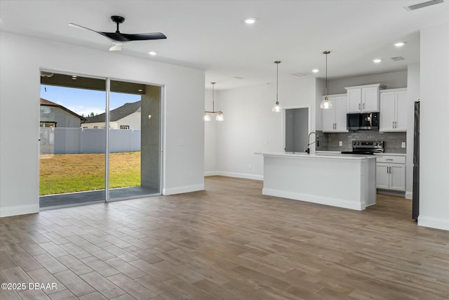 kitchen with white cabinetry, a center island with sink, stainless steel electric stove, and decorative light fixtures