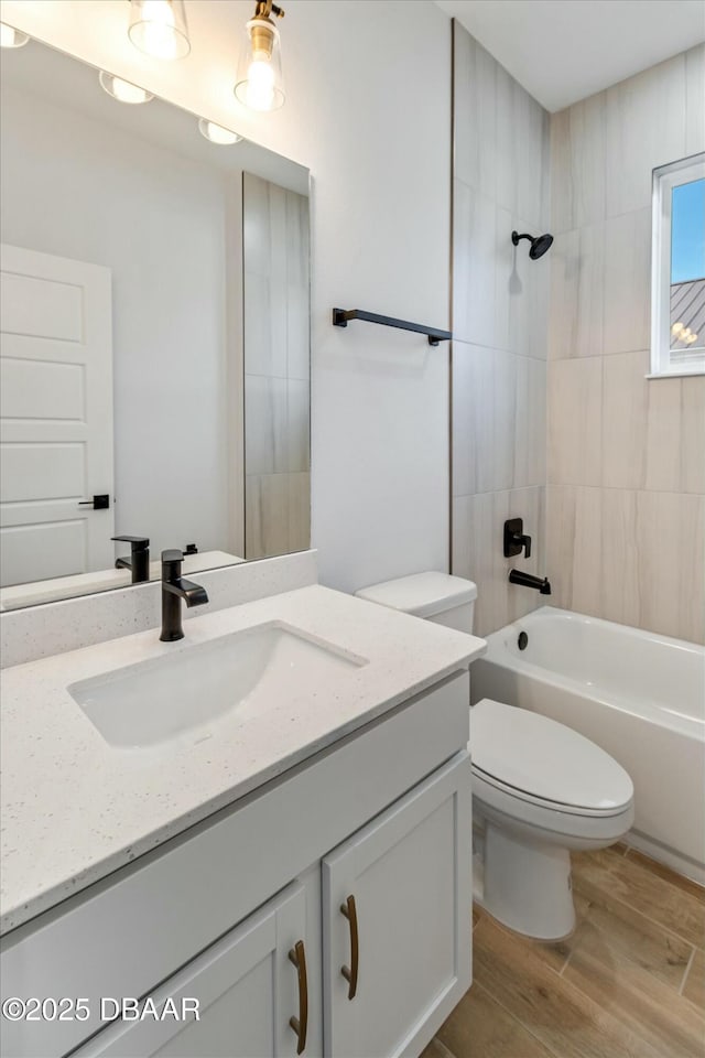 full bathroom featuring tiled shower / bath, hardwood / wood-style floors, vanity, and toilet