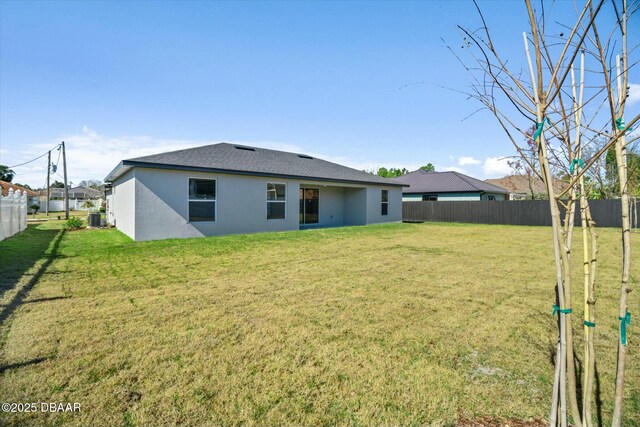 rear view of house with central AC and a yard