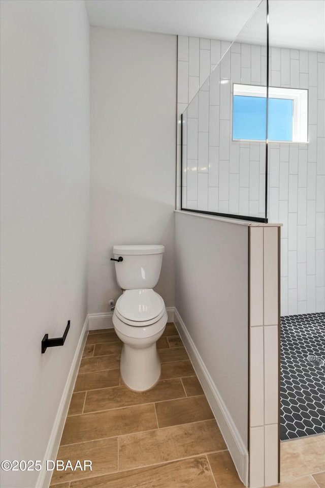 bathroom with a tile shower and toilet