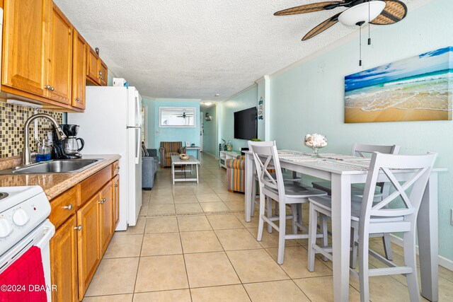 kitchen featuring a textured ceiling, tasteful backsplash, sink, light tile patterned flooring, and white range with electric stovetop