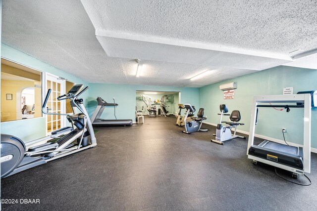 workout area featuring a wall mounted AC and a textured ceiling