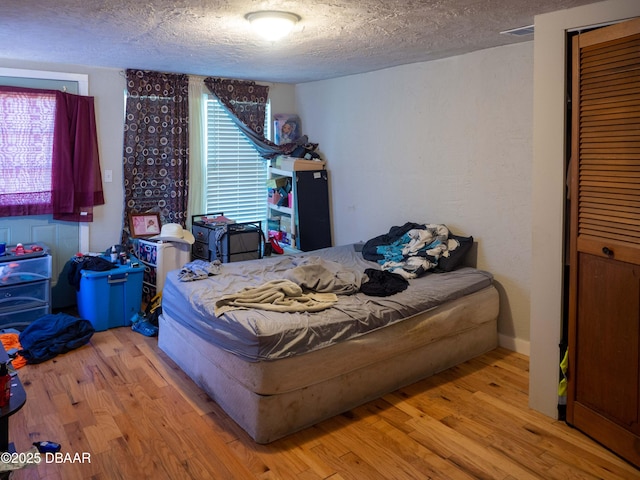 bedroom with a textured ceiling and wood finished floors