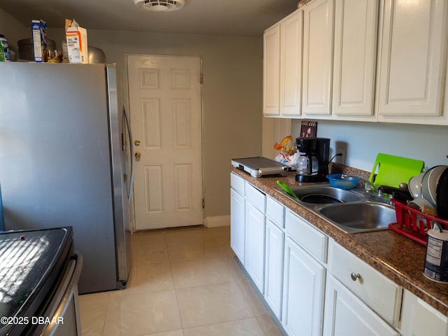 kitchen featuring a sink, white cabinetry, light tile patterned floors, and freestanding refrigerator