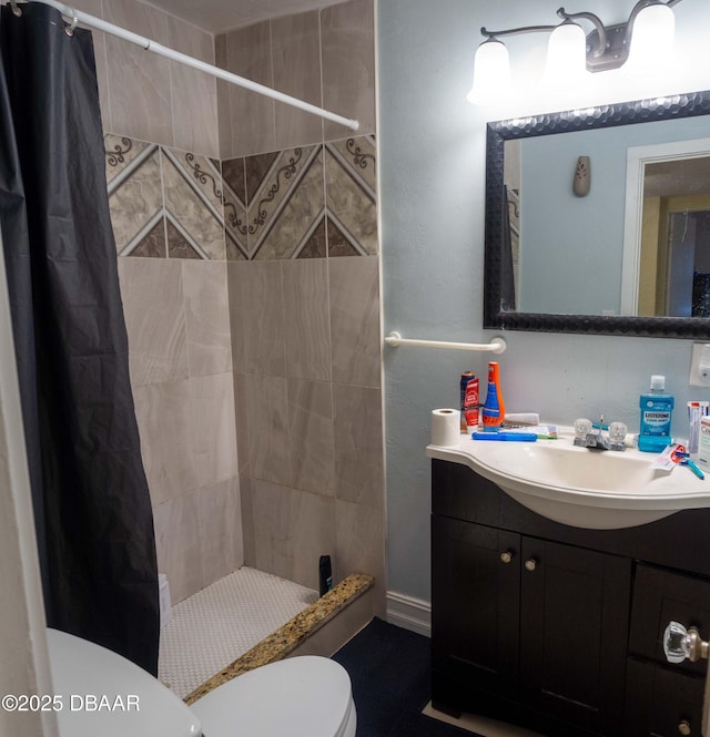 bathroom with vanity, toilet, and a tile shower