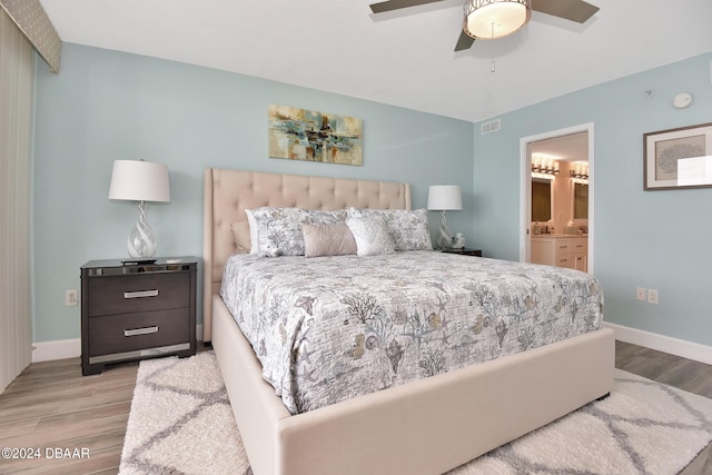 bedroom with ensuite bathroom, light hardwood / wood-style floors, and ceiling fan