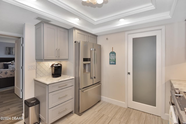 kitchen with high quality fridge, a tray ceiling, crown molding, gray cabinets, and decorative backsplash