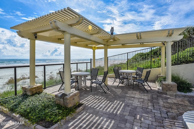 view of patio / terrace featuring a beach view, a water view, and a pergola