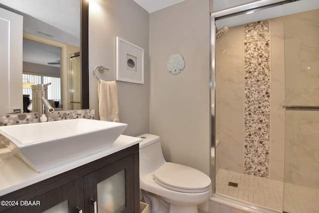 bathroom with a shower with door, vanity, and toilet