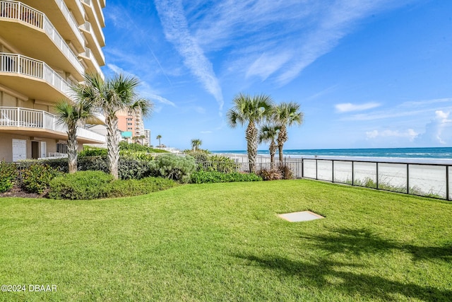 view of yard with a beach view, a water view, and a balcony