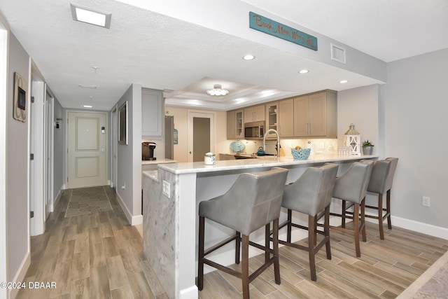 kitchen with kitchen peninsula, light hardwood / wood-style floors, a textured ceiling, and a breakfast bar