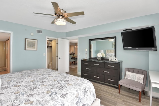 bedroom with light hardwood / wood-style floors, ceiling fan, a spacious closet, and a closet