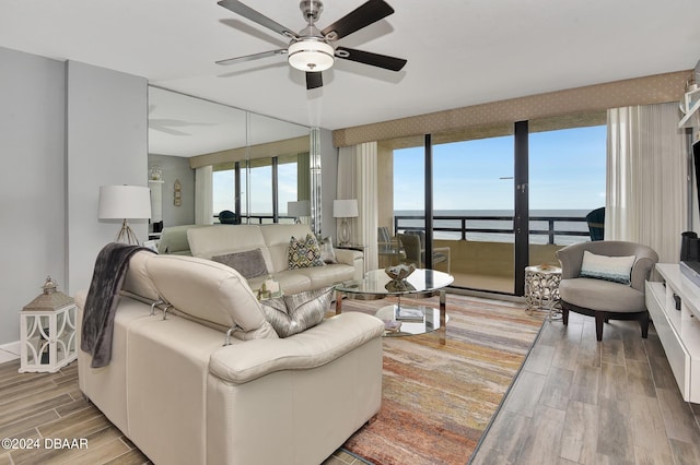 living room with a water view, ceiling fan, and wood-type flooring