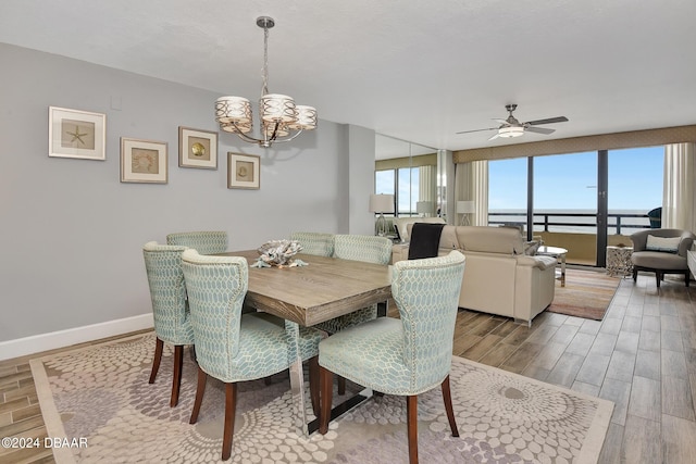 dining area featuring a water view, hardwood / wood-style flooring, and ceiling fan with notable chandelier