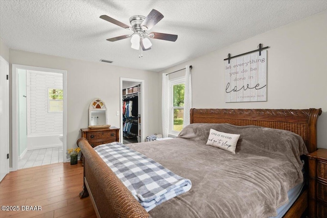 2455 Whooping Crane Dr, Deleon Springs, FL 32130 - bedroom featuring wood-type flooring, a walk in closet, a textured ceiling, a closet, and ensuite bathroom