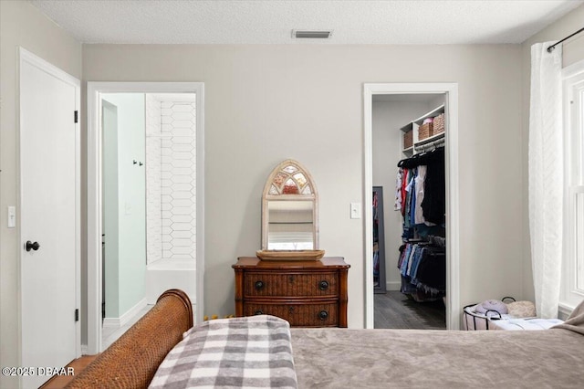 2455 Whooping Crane Dr, Deleon Springs, FL 32130 - bedroom featuring a walk in closet, wood finished floors, a closet, and ensuite bath
