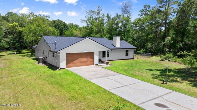 2455 Whooping Crane Dr, Deleon Springs, FL 32130 - view of front facade with board and batten siding, a chimney, a garage, driveway, and a front yard