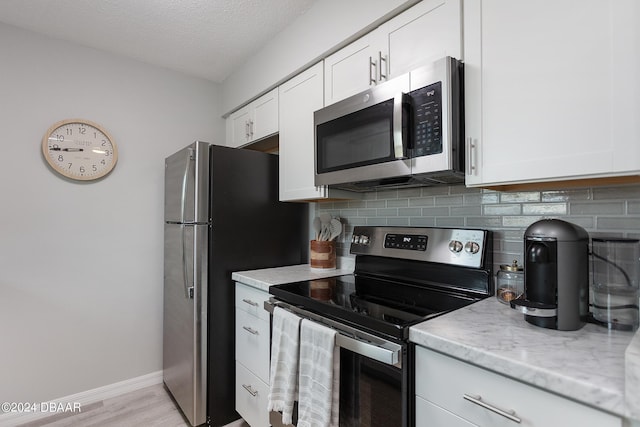 3750 S Atlantic Ave Unit 180, Daytona Beach Shores, FL 32118 - kitchen with stainless steel appliances, decorative backsplash, white cabinets, baseboards, and a textured ceiling