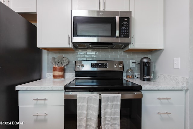 kitchen featuring stainless steel appliances, white cabinets, and backsplash