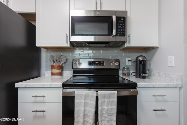 3750 S Atlantic Ave Unit 180, Daytona Beach Shores, FL 32118 - kitchen with appliances with stainless steel finishes, backsplash, white cabinets, and light stone counters