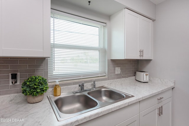 kitchen with white cabinetry, sink, tasteful backsplash, and light stone countertops