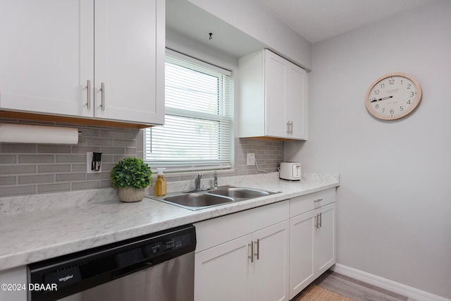 kitchen featuring light hardwood / wood-style floors, dishwasher, white cabinets, sink, and backsplash