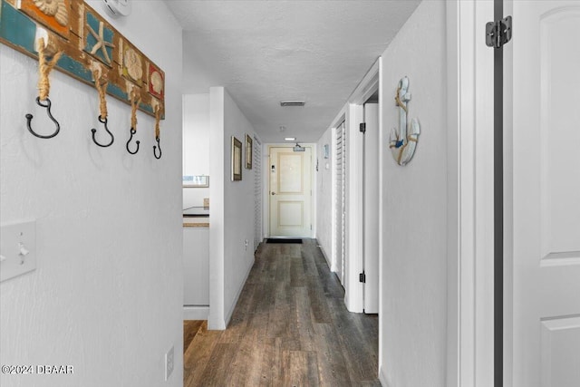 hallway with dark hardwood / wood-style flooring and a textured ceiling