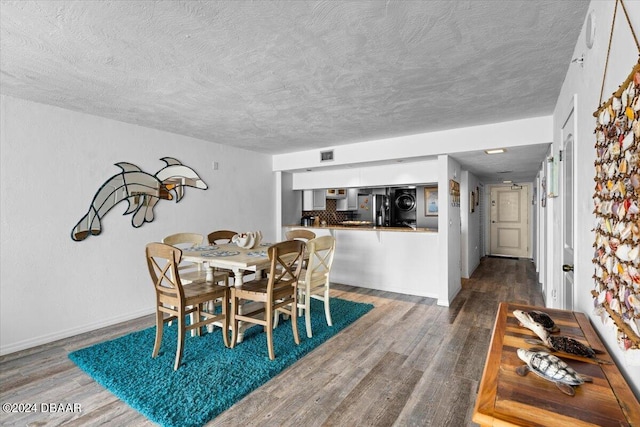 dining space featuring wood-type flooring and a textured ceiling