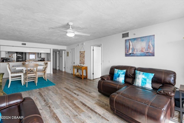 living room with hardwood / wood-style floors, ceiling fan, and a textured ceiling