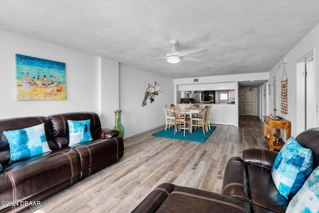 living room with a textured ceiling, wood-type flooring, and ceiling fan