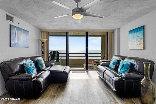 living room with a water view, wood-type flooring, floor to ceiling windows, and a textured ceiling