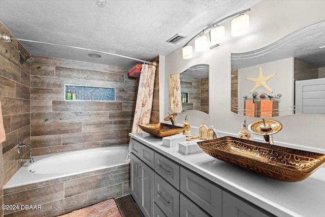 bathroom with shower / bath combo, vanity, and a textured ceiling