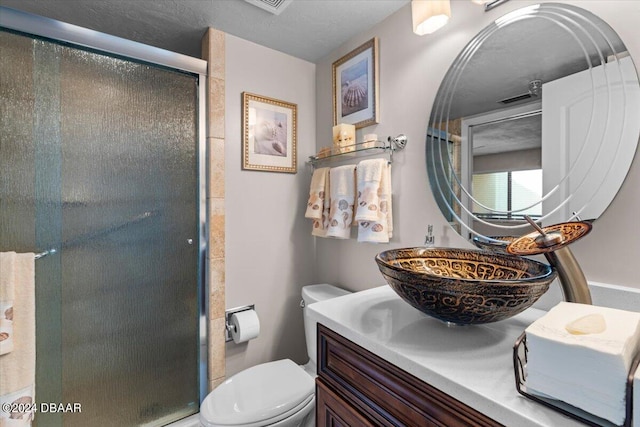 bathroom featuring toilet, vanity, and a shower with shower door