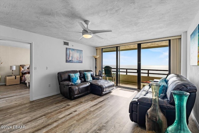 living room with hardwood / wood-style floors, a wealth of natural light, a water view, and ceiling fan