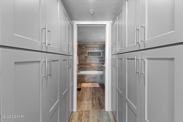 interior space featuring a washtub, wooden walls, a textured ceiling, and hardwood / wood-style flooring