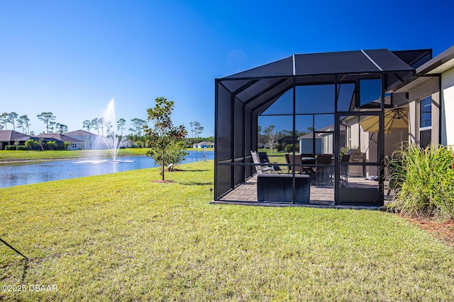 view of yard with glass enclosure, a water view, and a patio