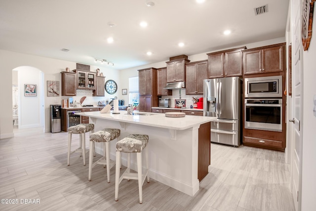 kitchen with a center island with sink, sink, a kitchen bar, and stainless steel appliances