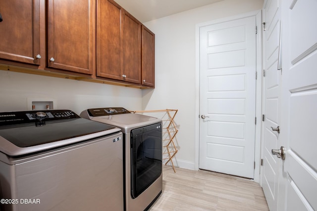 laundry area featuring cabinets, independent washer and dryer, and light hardwood / wood-style flooring