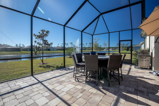 view of patio with a water view, grilling area, and a lanai