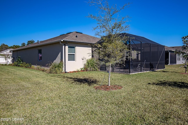 back of property featuring a lawn, glass enclosure, and a patio